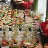 Gläschen mit Obstsalat und Platten mit belegten Broten.