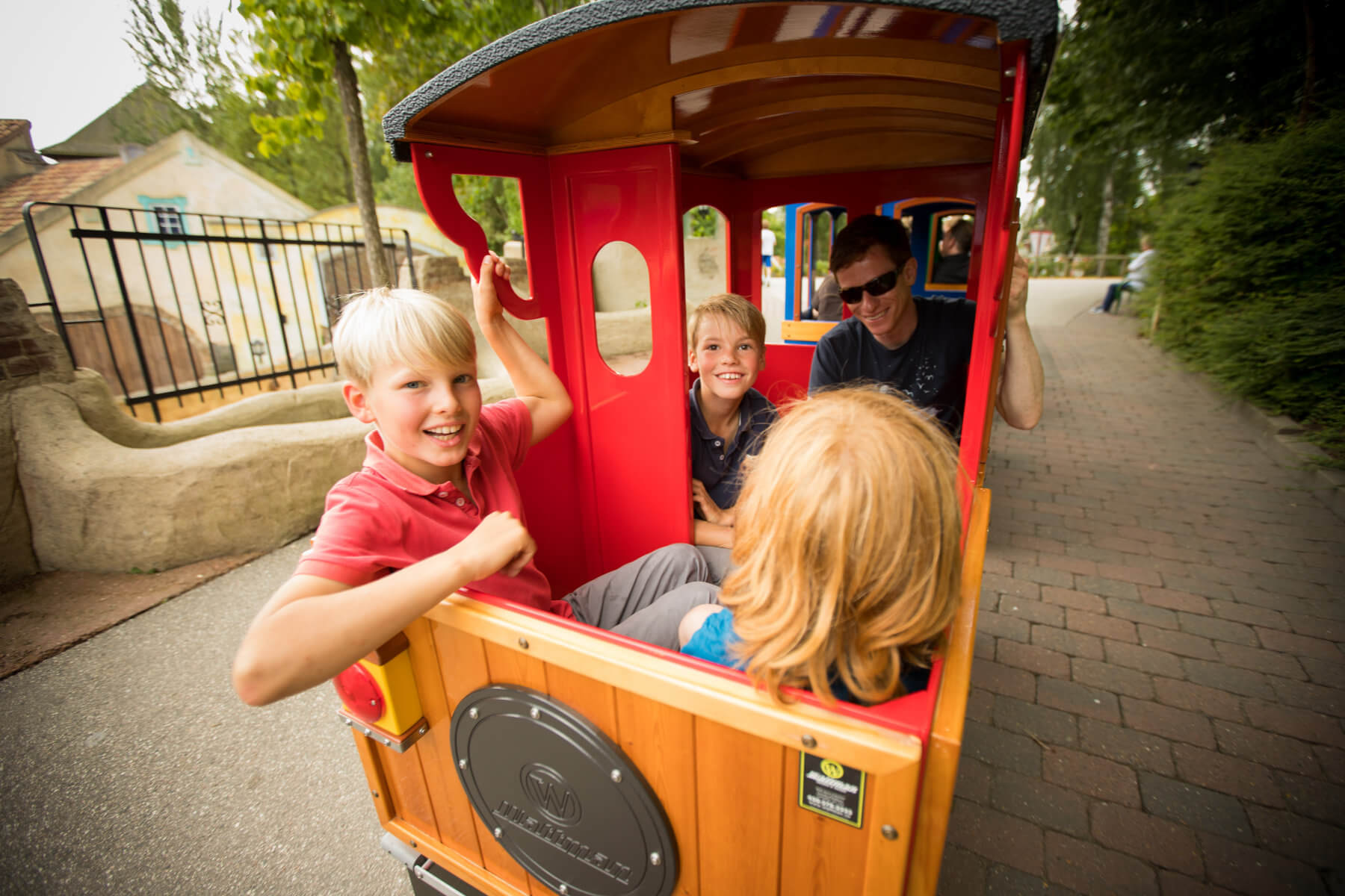 Ein Mann und drei Kinder sitzen in einem Zug der durch den HANSA-PARK fährt.