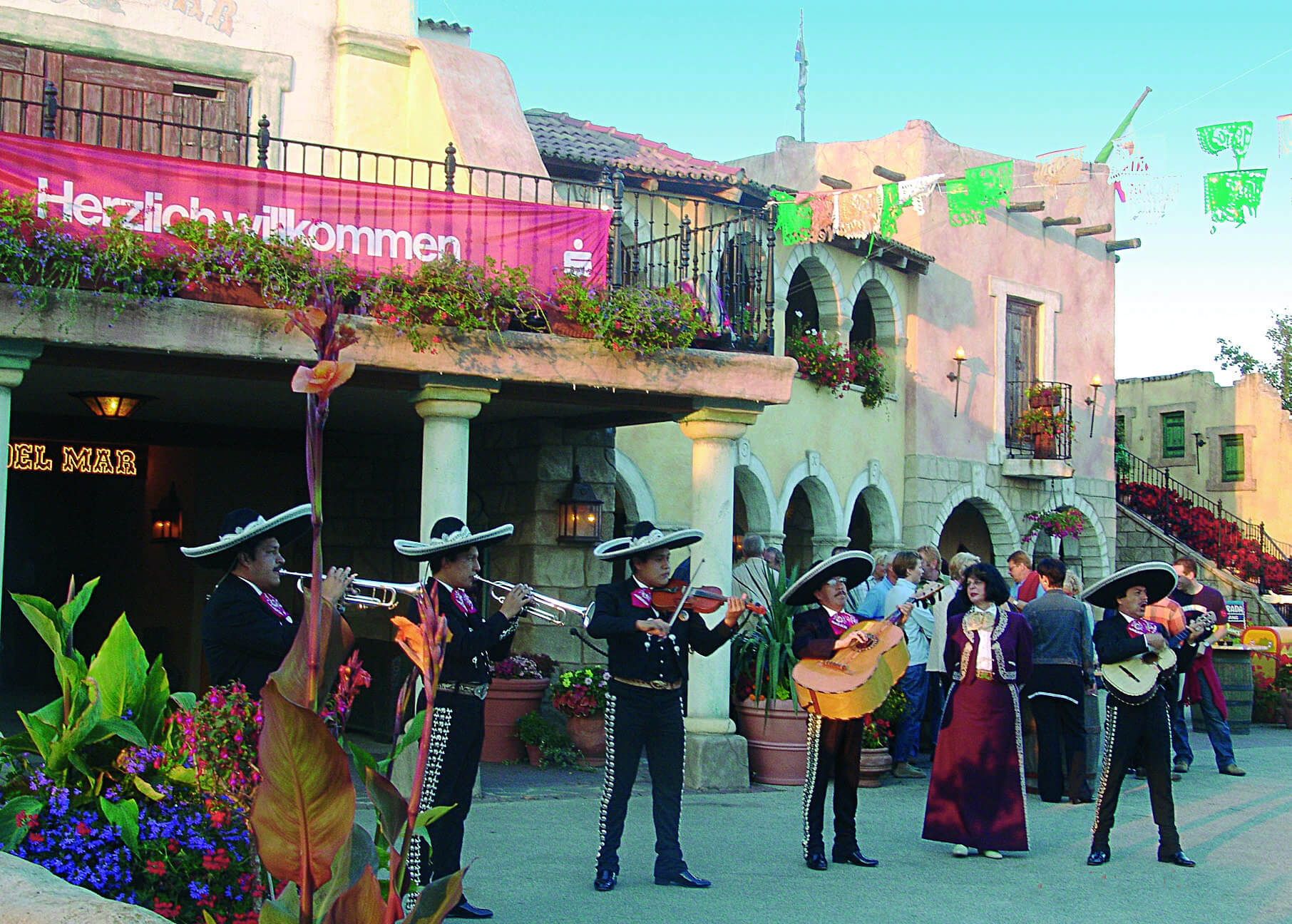 Eine Mariachi Band spielt vor der Arena del Mar. Leute stehen dahinter und unterhalten sich.